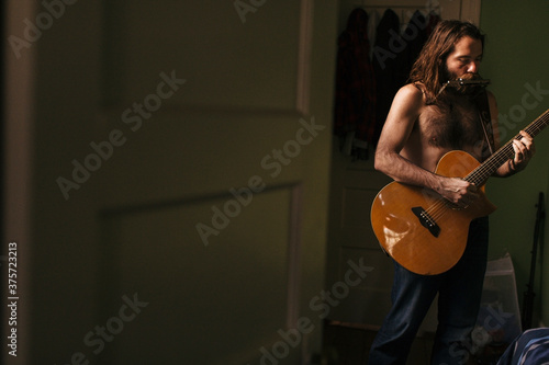 A soulful scruffy musician plays instruments photo