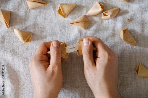 Hands holding fortune cookie message reading 