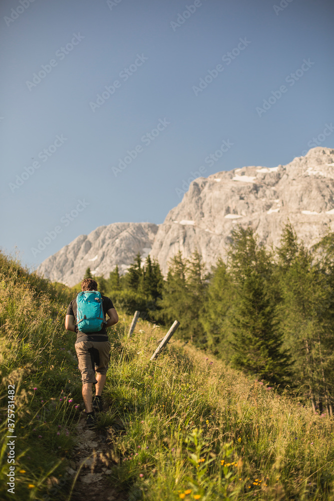 A young man is hiking a trail up a mountain A young man is hiking a trail up a mountain