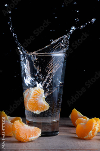 splash in the water with an orange. an orange falls into a glass of water. Citrus Splash in Water