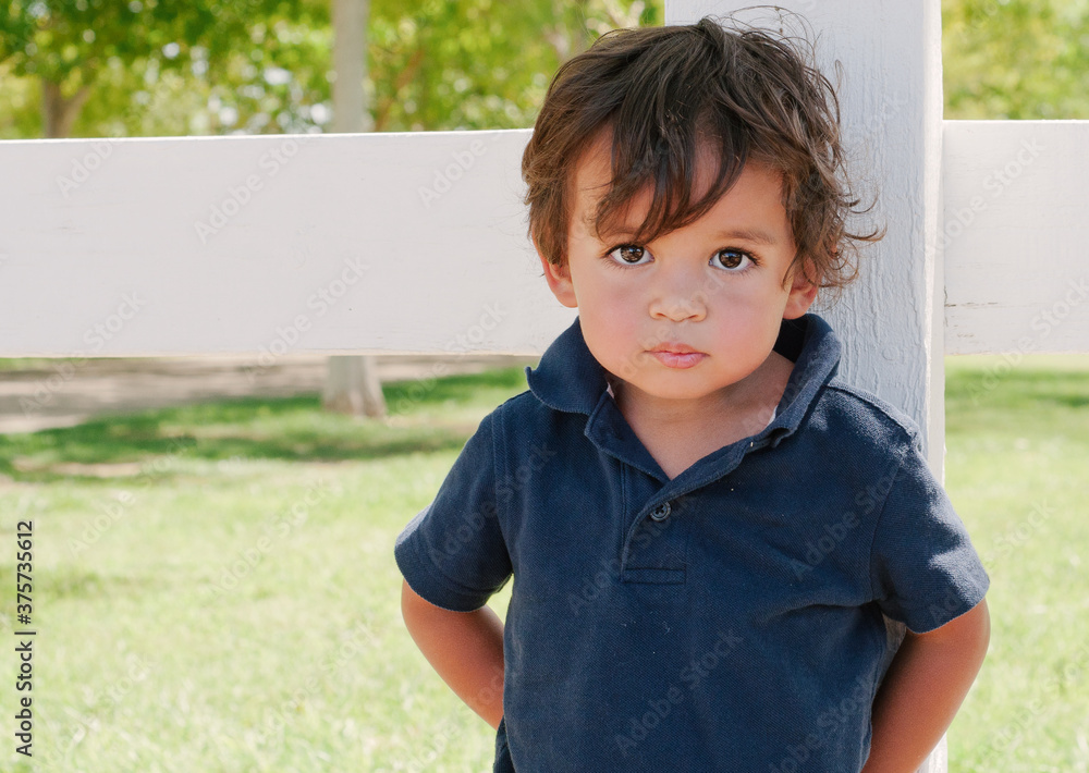 toddler mestizo boy stands by a fence toddler mestizo boy stands by a fence
