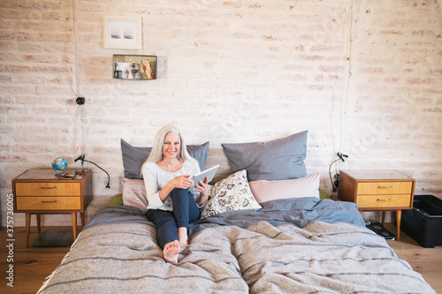 Senior woman on her bed with tablet pc