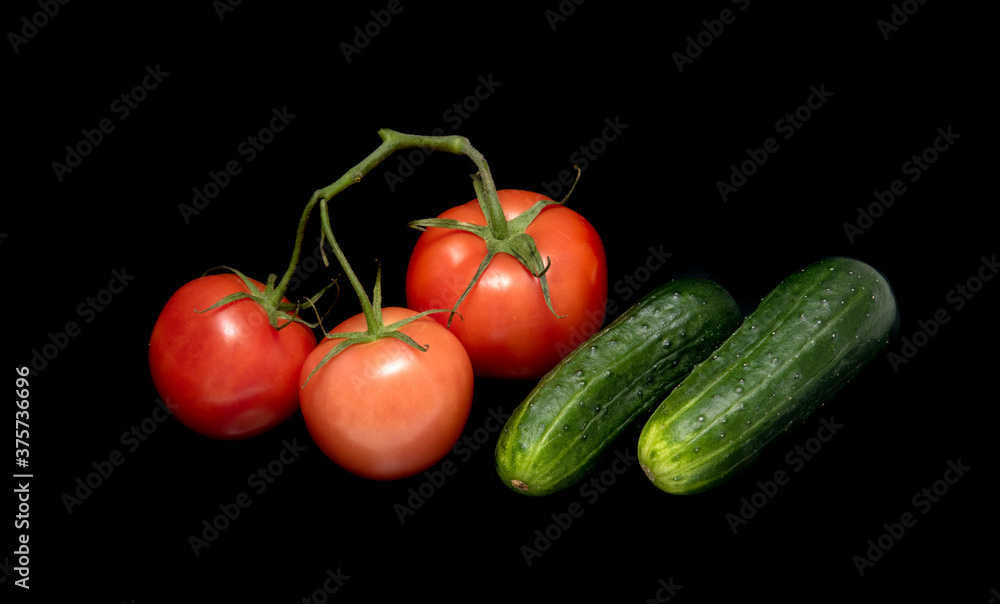 Red tomato and green cucumber isolated on a black background. Red tomato and green cucumber isolated on a black background.