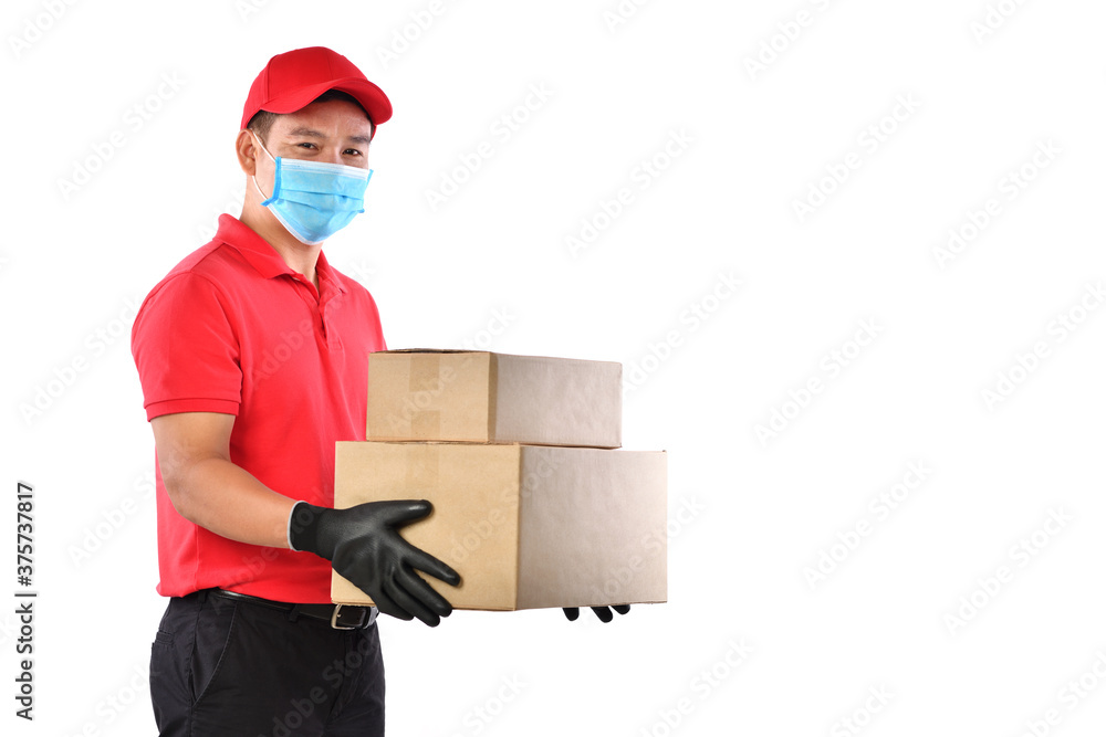 Happy young Asian delivery man in red uniform, medical face mask, protective gloves carry cardboard box in hands isolated on white background. Delivery guy give parcel shipment. Safe delivery Happy young Asian delivery man in red uniform, medical face mask, protective gloves carry cardboard box in hands isolated on white background. Delivery guy give parcel shipment. Safe delivery