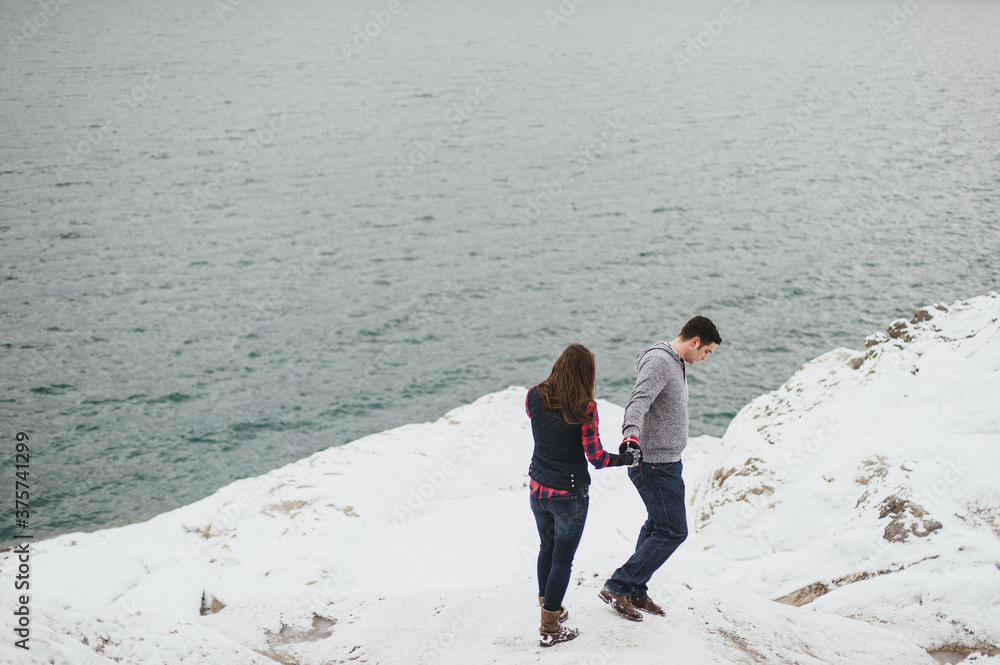 Young adventurous couple holding hands in winter snow covered landscape Young adventurous couple holding hands in winter snow covered landscape