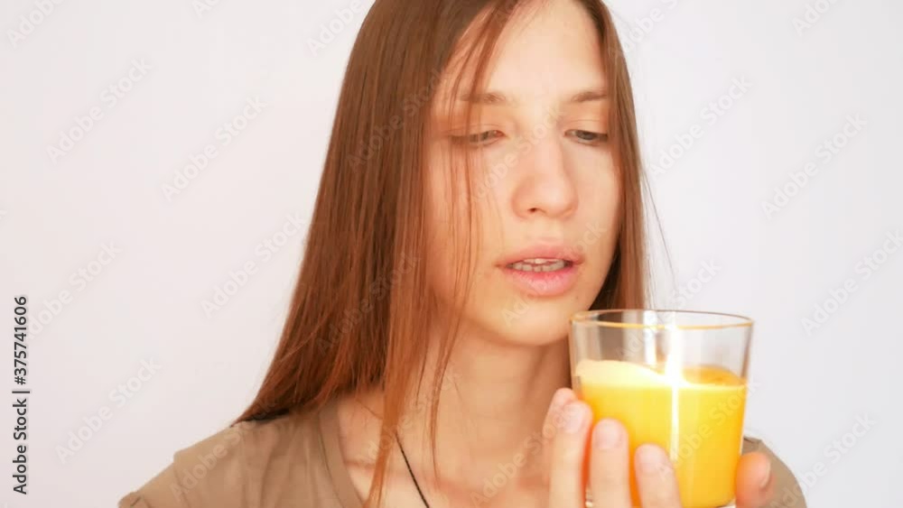 A beautiful young woman blows out a scented candle and enjoys the fragrance against white background A beautiful young woman blows out a scented candle and enjoys the fragrance against white background