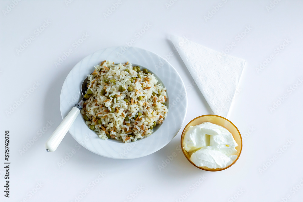 Traditional Turkish rice pilaf with peas and noodles on white with yogurt and compote Traditional Turkish rice pilaf with peas and noodles on white with yogurt and compote