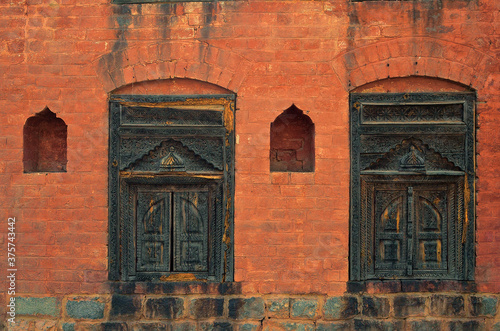 A red bricked wall with some old designed wooden windows photo