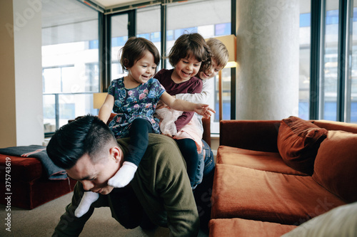 Young father having fun playing with three kids inside photo