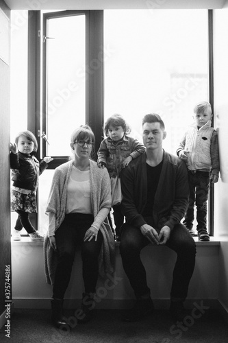 Young family of five sitting together in window sill - looking serious photo