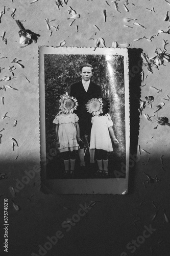 old photo in semi shade, family, children with flowers over their faces, hidden photo