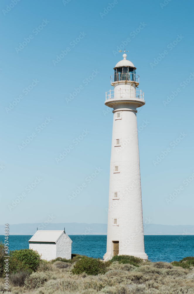 Bright white lighthouse by shallow coastline Bright white lighthouse by shallow coastline