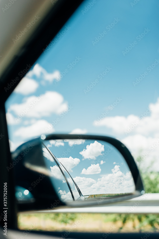 View of gorgeous summer clouds in the rearview mirror of a car View of gorgeous summer clouds in the rearview mirror of a car