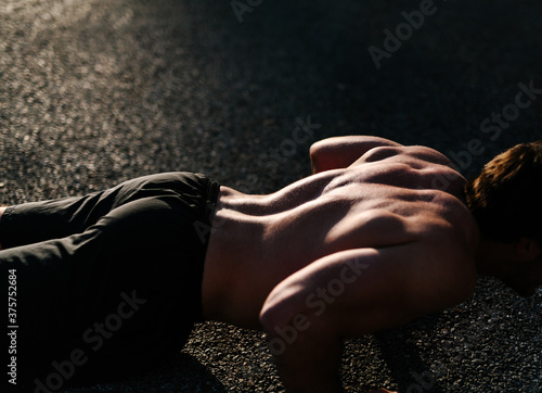 Back muscles flexing on athletic man doing pushup training exercise