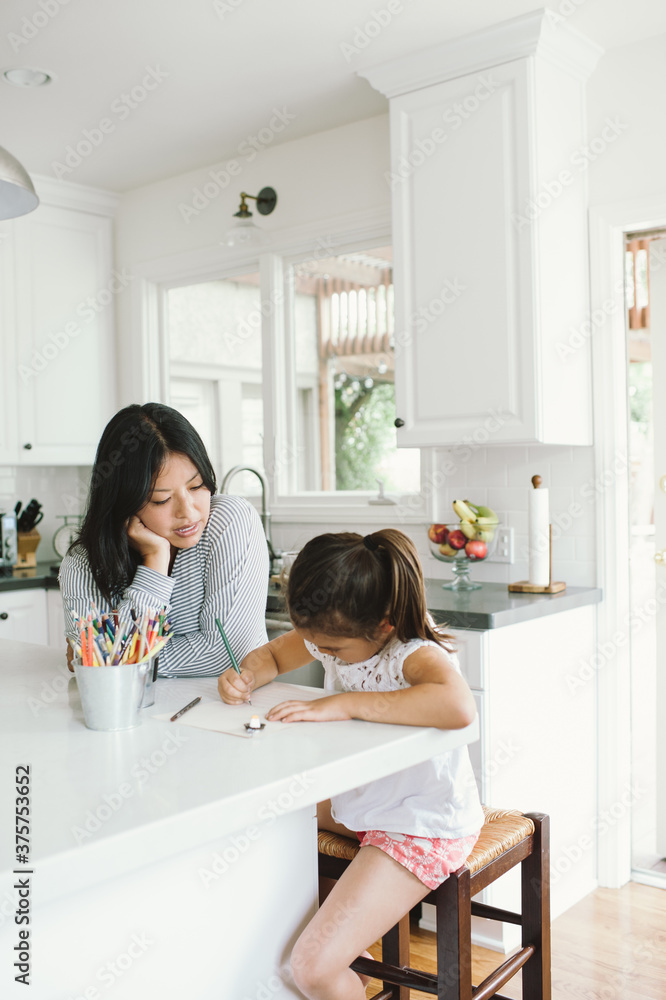 Mom doing homeschool lesson in kitchen with daughter Mom doing homeschool lesson in kitchen with daughter