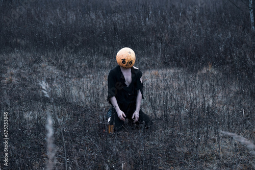 Lost in the woods a guy in a pumpkin with a lantern with a candle wanders in search of a means of getting rid of the autumn depression