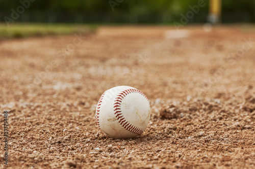 Baseball Sits In The Dirt Near First Base photo