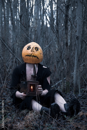 Lost in the woods a guy in a pumpkin with a lantern with a candle wanders in search of a means of getting rid of the autumn depression