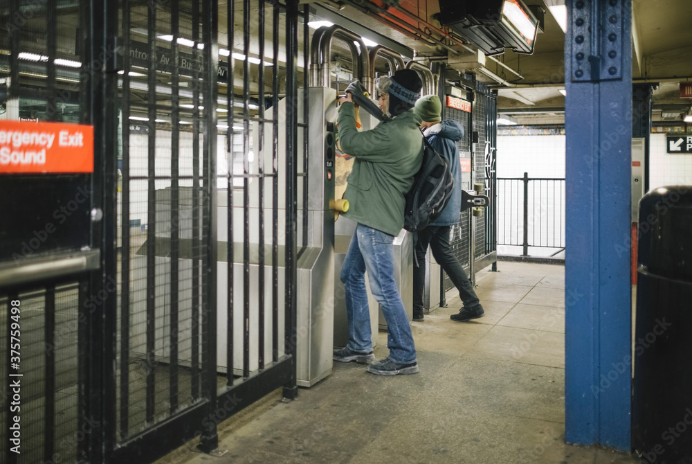 Young Commuters Going Through Turnstiles with Big Bag and Skateboard in New York Subway Young Commuters Going Through Turnstiles with Big Bag and Skateboard in New York Subway