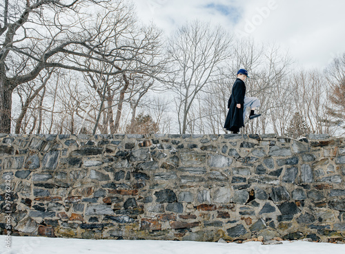Boy pretending to be a Union soldier marches on a tall stone wall