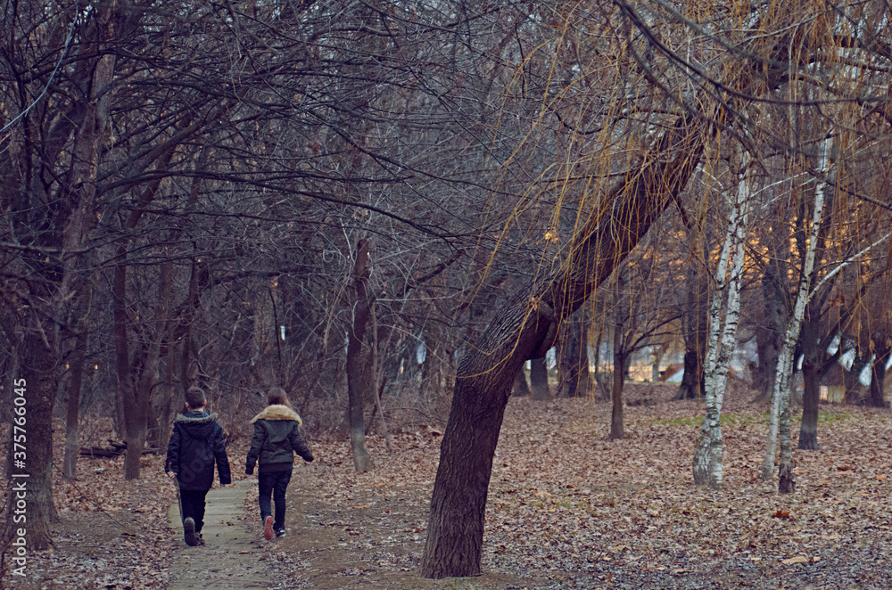 Boy and girl walking through the woods near the river in sunset Boy and girl walking through the woods near the river in sunset