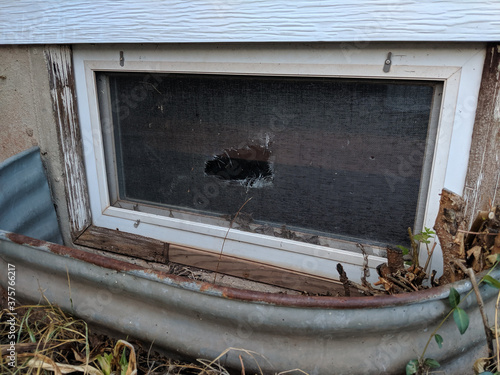 Ripped Hole in Old Window Screen of Rectangular Basement Window that Needs Repairs