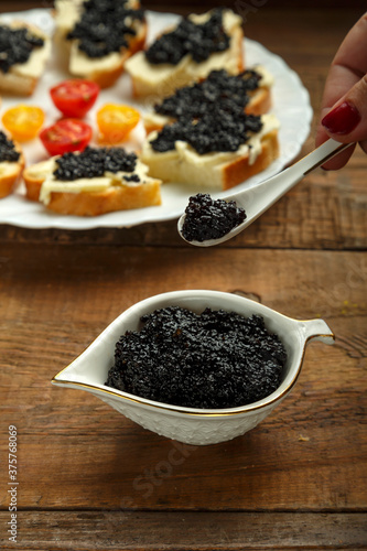 Spoon with black caviar in female caviar over caviar.
