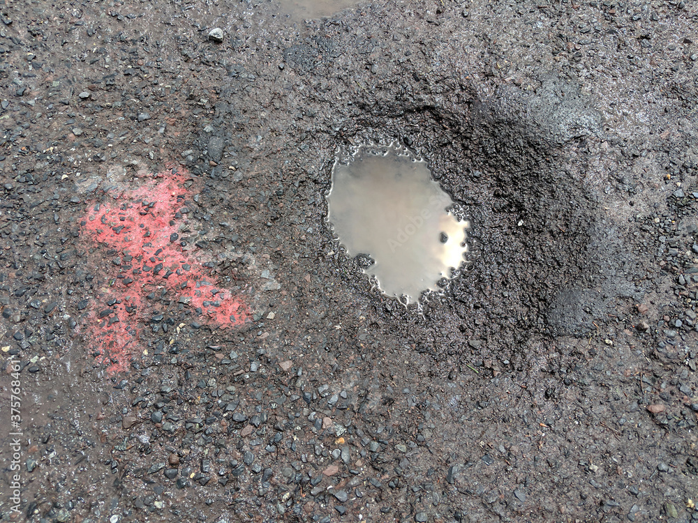 Foto de Asphalt Pothole Filled with Dirty Water Puddle in a Parking Lot