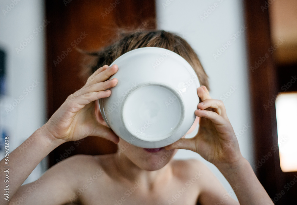 Boy drinks the milk from his cereal bowl Boy drinks the milk from his cereal bowl