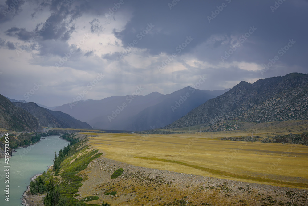 Majestic mountain landscape on a rainy summer or autumn day. Beautiful view of the bend of Katun river, plains and rocks. Torrents of rain, overcast sky. Natural backgrounds.