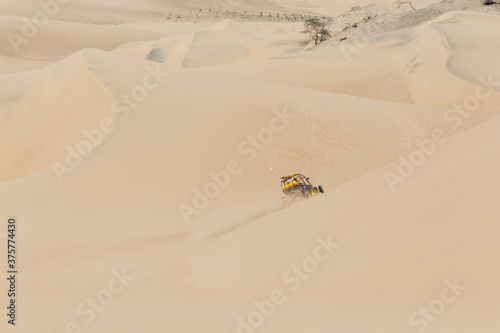 Dune buggy with passengers speeding across the side of a large d photo