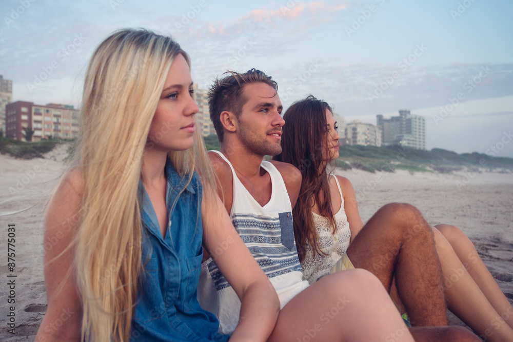 Three friends sitting on the beach waiting for Sunrise Three friends sitting on the beach waiting for Sunrise