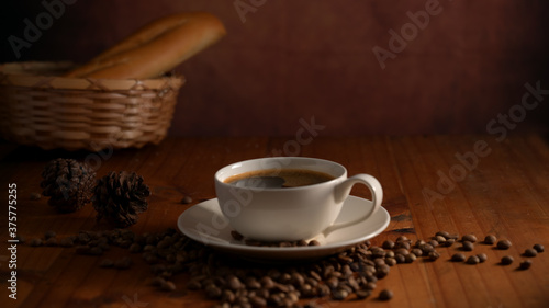 Close up view of a cup of hot coffee with baguette basket and coffee beans