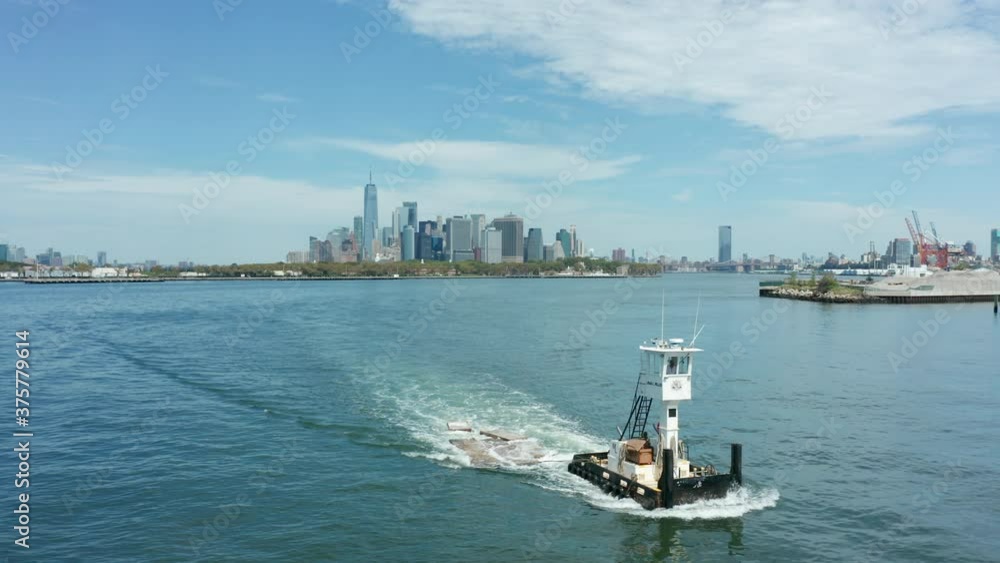 flying right in front of tugboat sailing away from Manhattan skyline flying right in front of tugboat sailing away from Manhattan skyline