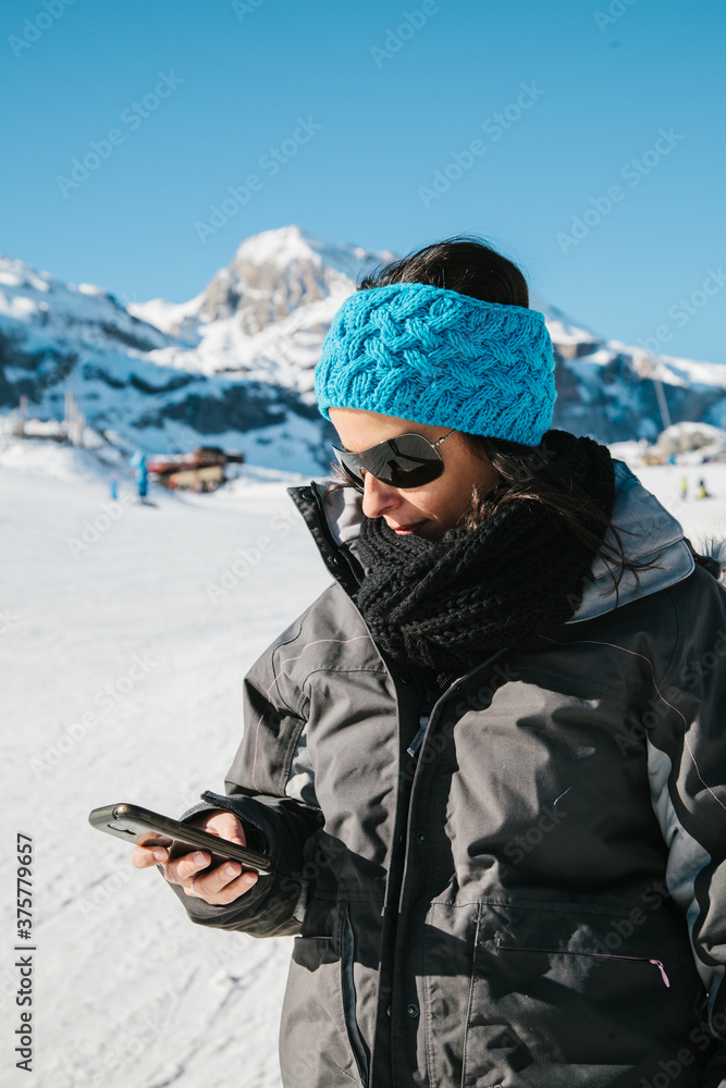 Woman Using Her Mobile Phone in a Sunny Snowy Scenery Woman Using Her Mobile Phone in a Sunny Snowy Scenery