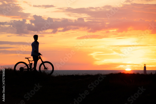 Silhouette of a young man with a Bicycle against the background of a sunset.