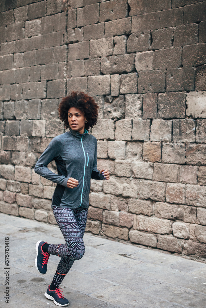 Young african american woman running on the city street. Young african american woman running on the city street.