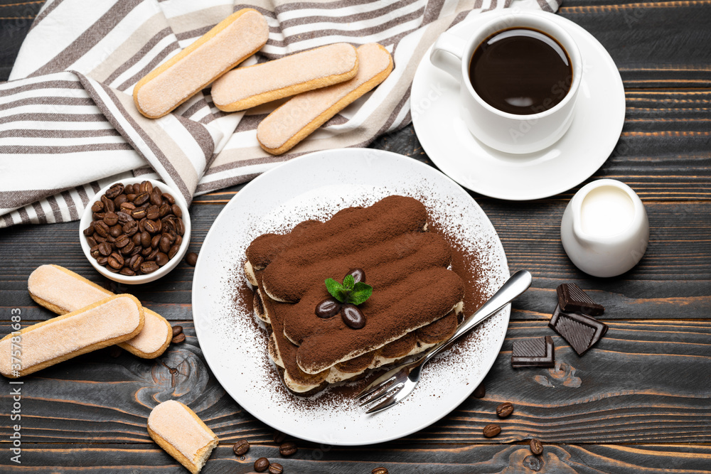 portion of Classic tiramisu dessert, cup of coffee and milk or cream on wooden background portion of Classic tiramisu dessert, cup of coffee and milk or cream on wooden background