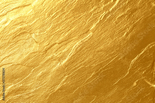 Details of golden texture background. Gold color painted on cement wall for background and wallpaper. Metal texture background in gold. Shiny yellow leaf gold foil texture background. Gold paint.