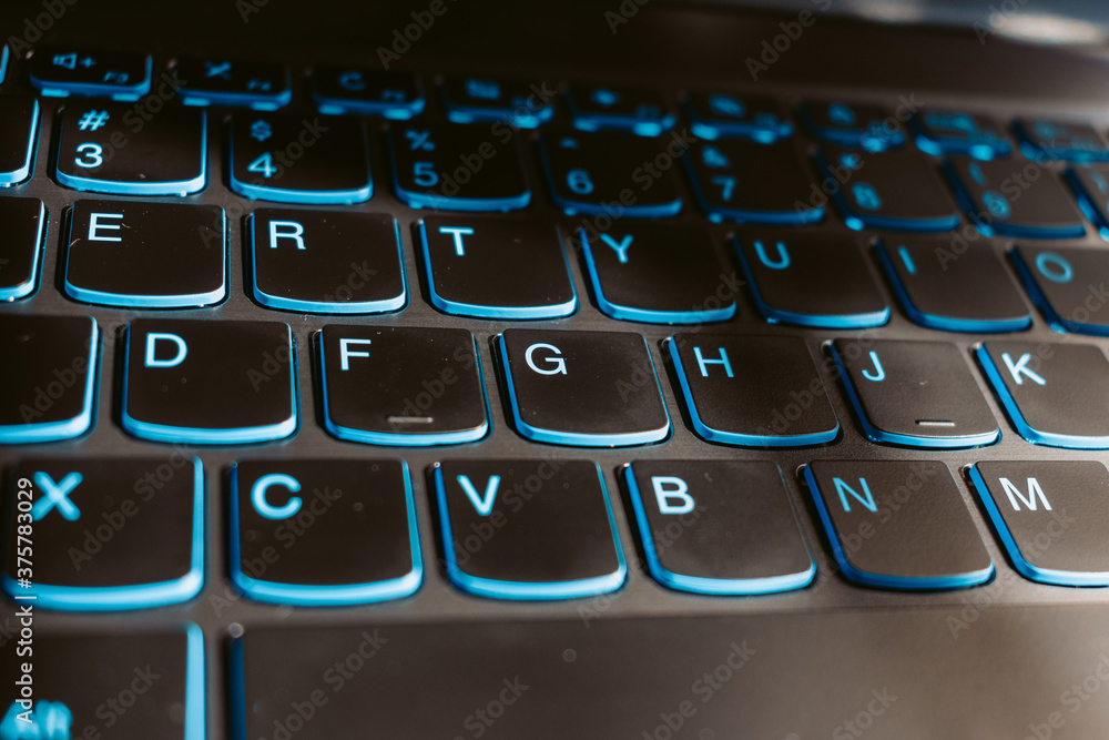 Close up shot of blue backlit laptop keyboard Close up shot of blue backlit laptop keyboard
