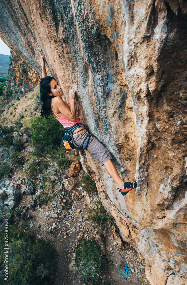 Female rock climber on a technical cliff in a mountain Female rock climber on a technical cliff in a mountain