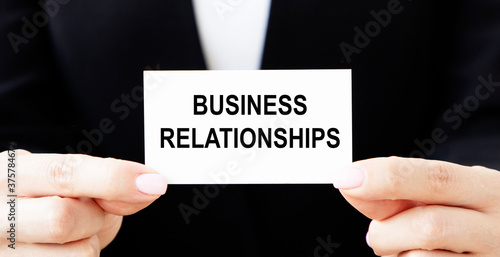 The businessman puts a business card in his pocket with the inscription BUSINESS RELATIONS.