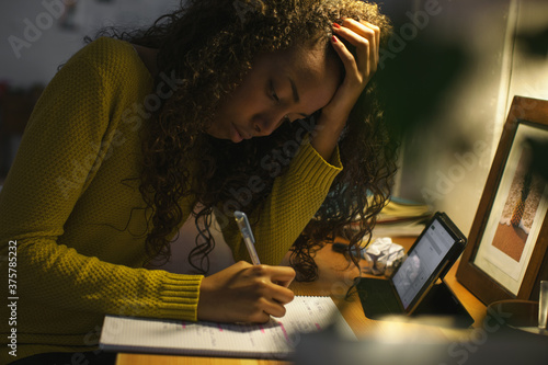 Young female student studying late at her desk at home. photo