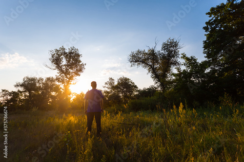 happy man see off evening sun  among a green summer prairie, human emotion concept background