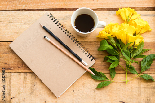 notebook planner for business work with hot coffee ,yellow flowers arrangement flat lay style at office on background wooden  photo