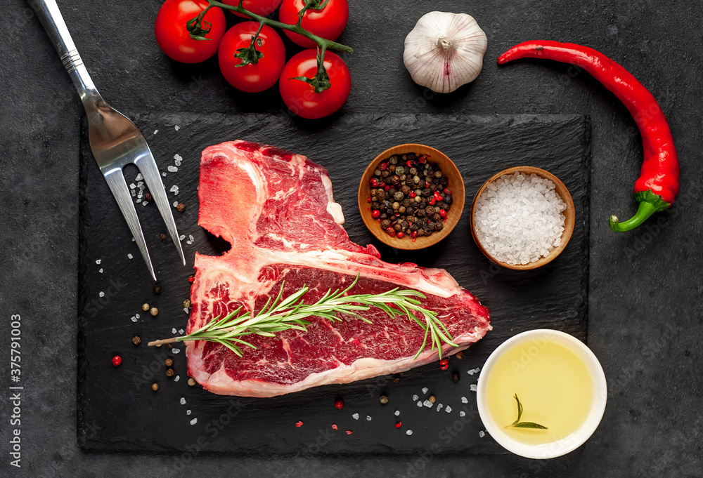 raw t-bone steak with ingredients  on stone background