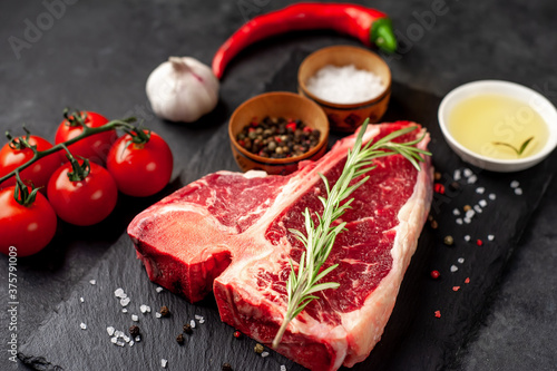 raw t-bone steak with ingredients  on stone background