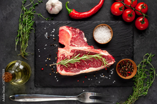 raw t-bone steak with ingredients on stone background