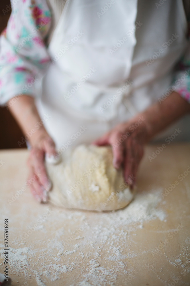 Blurred woman hands holding dough on wood pastry board Blurred woman hands holding dough on wood pastry board