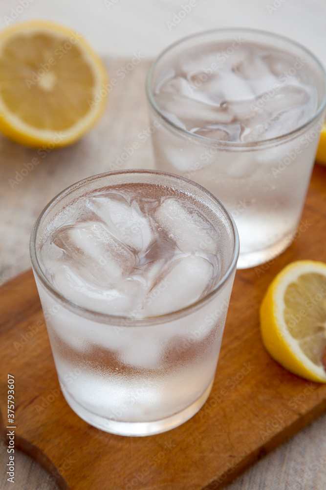 Fresh Lemon Sparkling Water with Ice on a rustic wooden board, side view. Fresh Lemon Sparkling Water with Ice on a rustic wooden board, side view.
